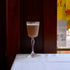 Glass of fall cocktail on a white surface with a blurred background