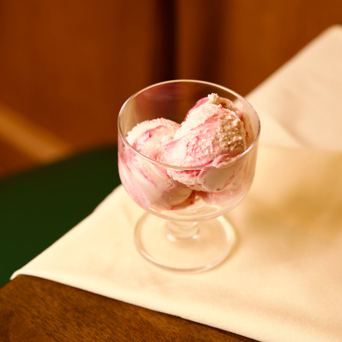 Hosteria dessert glass bowl with pink ice cream on a wooden surface